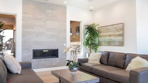 A modern living room with a fireplace, two sofas, a coffee table, and a large plant.