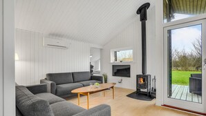 A modern living room with a grey sofa, a wooden coffee table, and a black wood-burning stove.