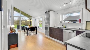 A modern kitchen with a large island, stainless steel appliances, and a view of the outdoors.