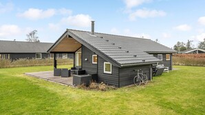 A modern house with a sloped roof, a covered patio, and a bicycle parked outside.