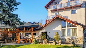 A two-story building with a stone facade, a balcony, and a wooden deck with picnic tables. - Cozy apartment in Jelesnia with WiFi (Jelesnia)