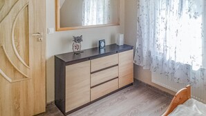 A bedroom with a wooden wardrobe, a bed, a mirror, and a window with floral curtains. - Cozy apartment in Jelesnia with WiFi (Jelesnia)
