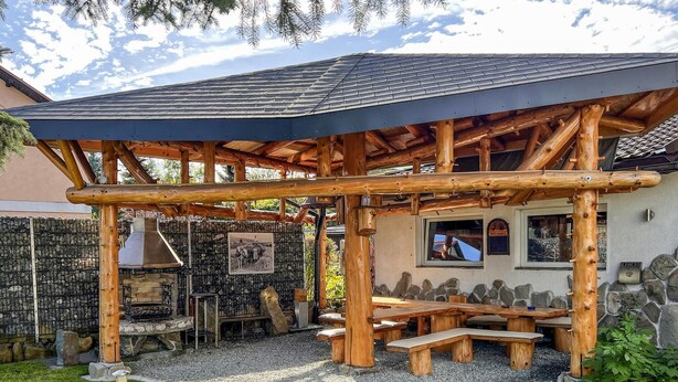 A wooden outdoor seating area with a stone wall and a stone fireplace. - Cozy apartment in Jelesnia with WiFi (Jelesnia)