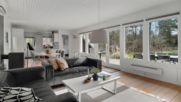En moderne stue med sofa, sofabord og spiseplads.