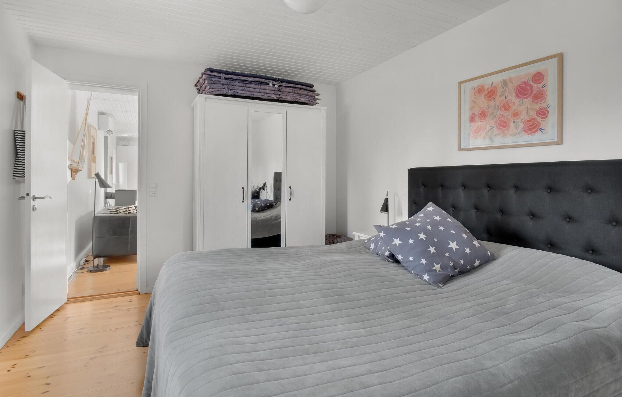 Une chambre à coucher avec un grand lit, une armoire et un tableau accroché au mur.