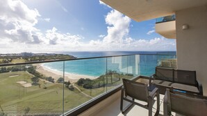 A balcony with a glass railing overlooking a beach and ocean. - A-1402 STUNNING 1 BEDROOM (Cupecoy)