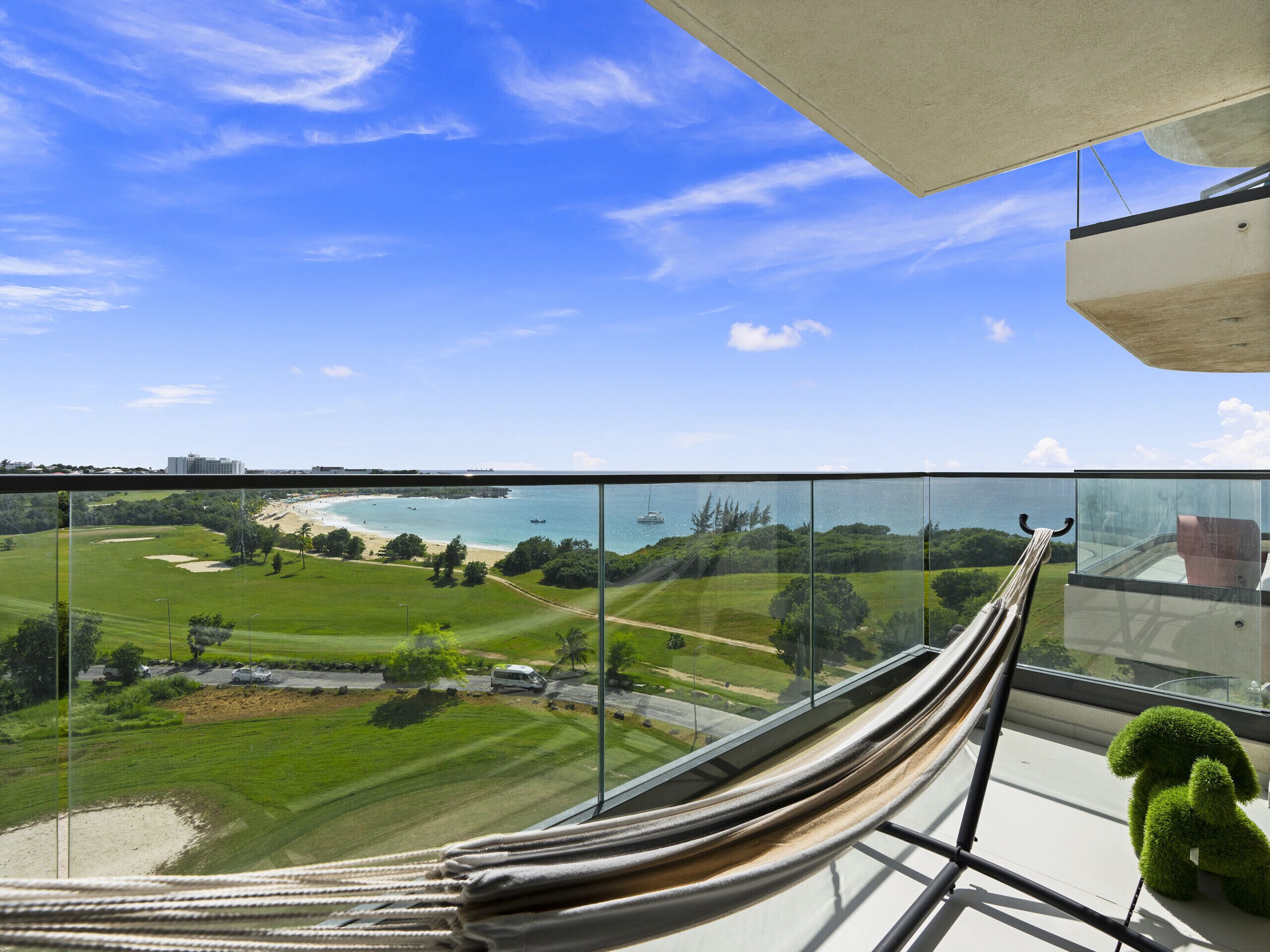 Ein Balkon mit Blick auf einen Golfplatz, Strand und Meer.