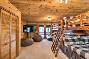 Cozy cabin-style room with a bunk bed, TV, and large window offering a view of the outdoors.