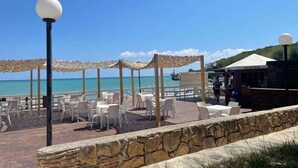 An outdoor seating area with tables and chairs, a stone wall, and a view of the ocean. - Mobilehome with air conditioning, terrace and pool (Peschici)