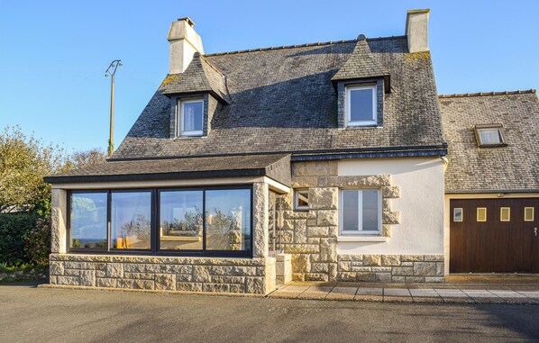 Une maison à deux étages avec une façade en pierre, une grande baie vitrée et une porte de garage.