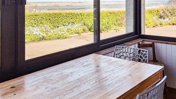 A room with a large window overlooking a landscaped area with a view of the sea.