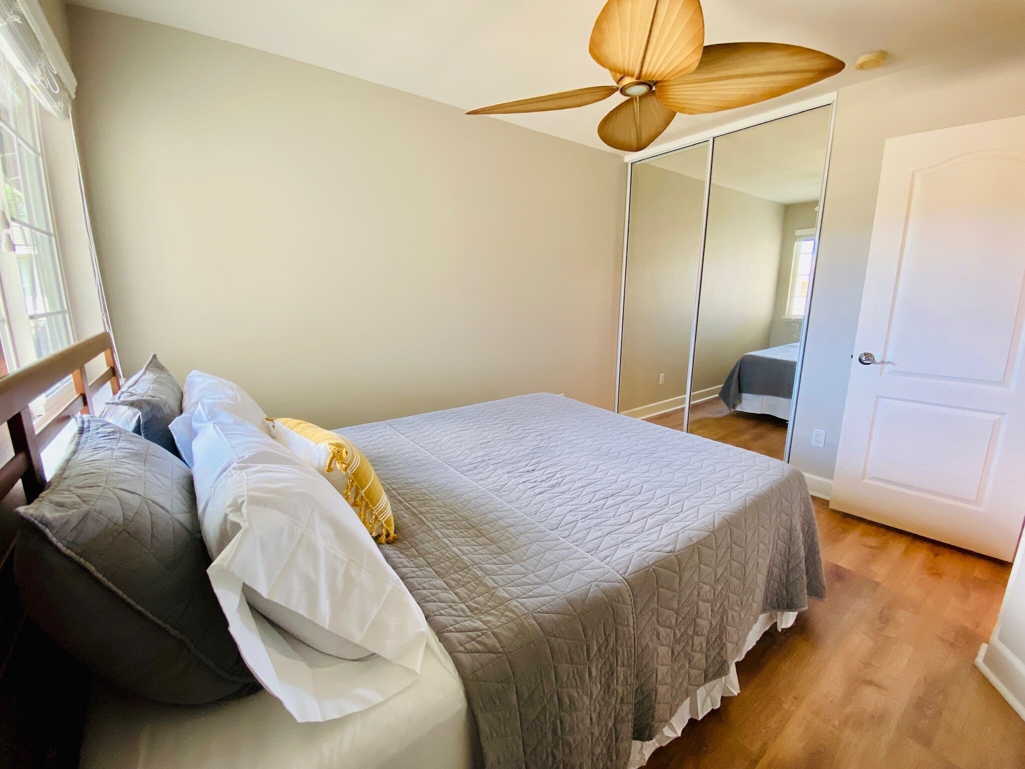 A bedroom with a bed, a ceiling fan, a wardrobe, and a door.