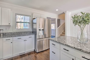 Enjoy cooking in this well-equipped kitchen with a refrigerator, water dispenser, and granite countertop.