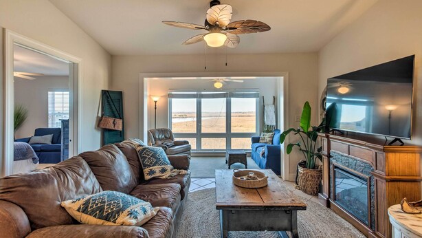 A spacious living room with a leather couch, a coffee table, a fireplace, and a television. - 3rd-Floor Riverfront Condo: Walk to Downtown Eats! (Darien)