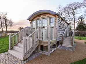 A wooden cabin with a curved roof, a wooden staircase, and a deck. - The Storyteller (York)