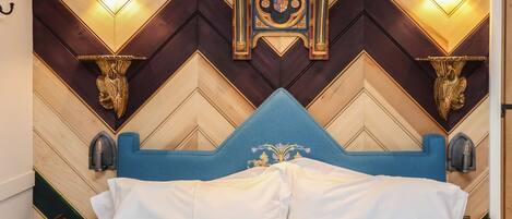 Un lit avec une tête de lit bleue, des murs en bois ornés de motifs géométriques et des luminaires fixés au mur.