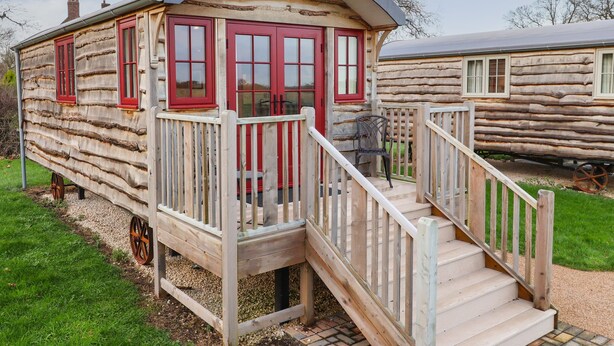 A rustic log cabin with a wooden deck and a small staircase leading to a porch. - The White Princess (York)