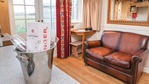 A cozy room with a leather sofa, a metal bucket with champagne glasses, a wooden table, and a large mirror on the wall. - The White Princess (York)