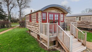 A log cabin with a porch and steps leading to a door with red trim. - The White Princess (York)