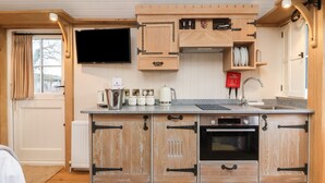 A compact kitchen with wooden cabinets, a Bosch oven, a built-in TV, and a fire blanket. - The White Princess (York)