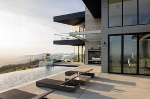 A modern building with a rooftop infinity pool, outdoor seating, and a scenic mountain view. - Belleza by Avantstay Hilltop Mansion w/ Pool, Panoramic Views & Ultra Modern Interior (Glen Ellen)