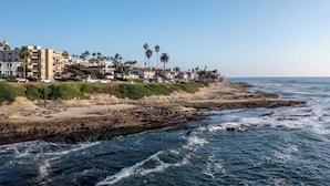 A coastal town with buildings along the beach, rocky shoreline, and waves crashing onto the shore. - Oceanfront in La Jolla, Steps to Beach, Shops, Dining Dawn Patrol by Avantstay (La Jolla)