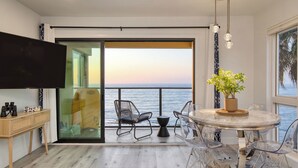 A balcony with a view of the sea, a dining table with chairs, a potted plant, and a television on a stand. - Oceanfront in La Jolla, Steps to Beach, Shops, Dining Dawn Patrol by Avantstay (La Jolla)