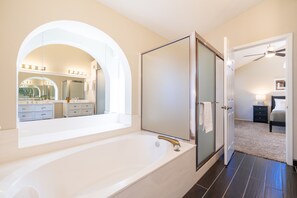 A modern bathroom with a large bathtub, a glass shower enclosure, and a vanity with a mirror.