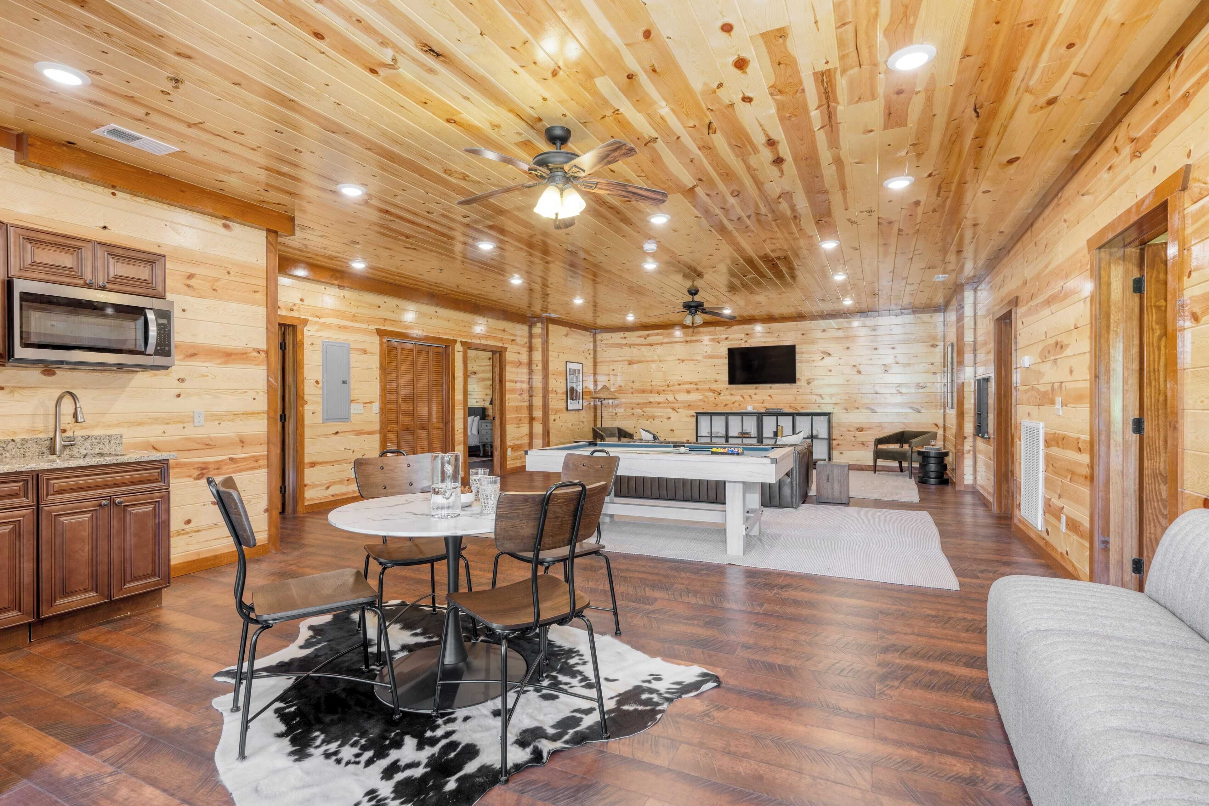 A spacious wooden cabin with a dining area, kitchen, and a pool table.