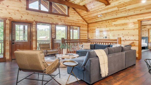 A wooden cabin interior with a sofa, chairs, a small table, and a balcony. - Ridge View by Avantstay15mins From Pigeon Forge w/ Pavilion, Indoor Pool & Hot Tub! (Sevierville)