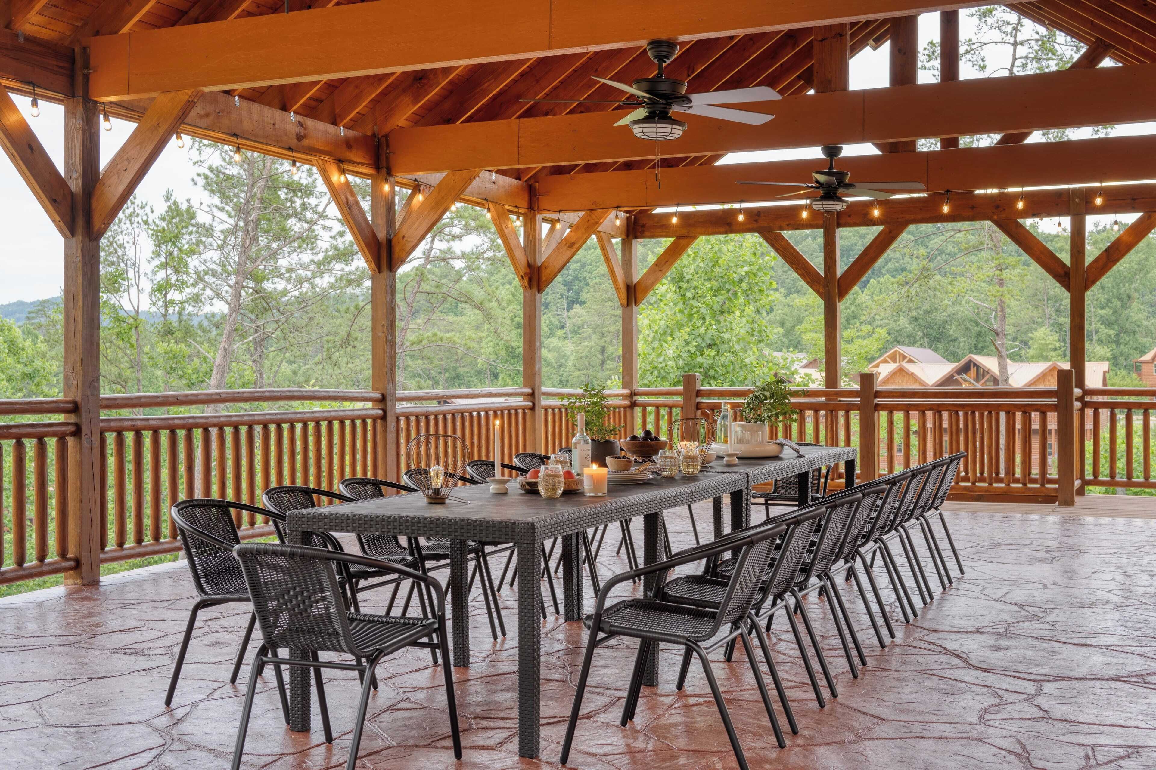 Un patio techado al aire libre con una mesa de comedor, sillas y luces colgantes.