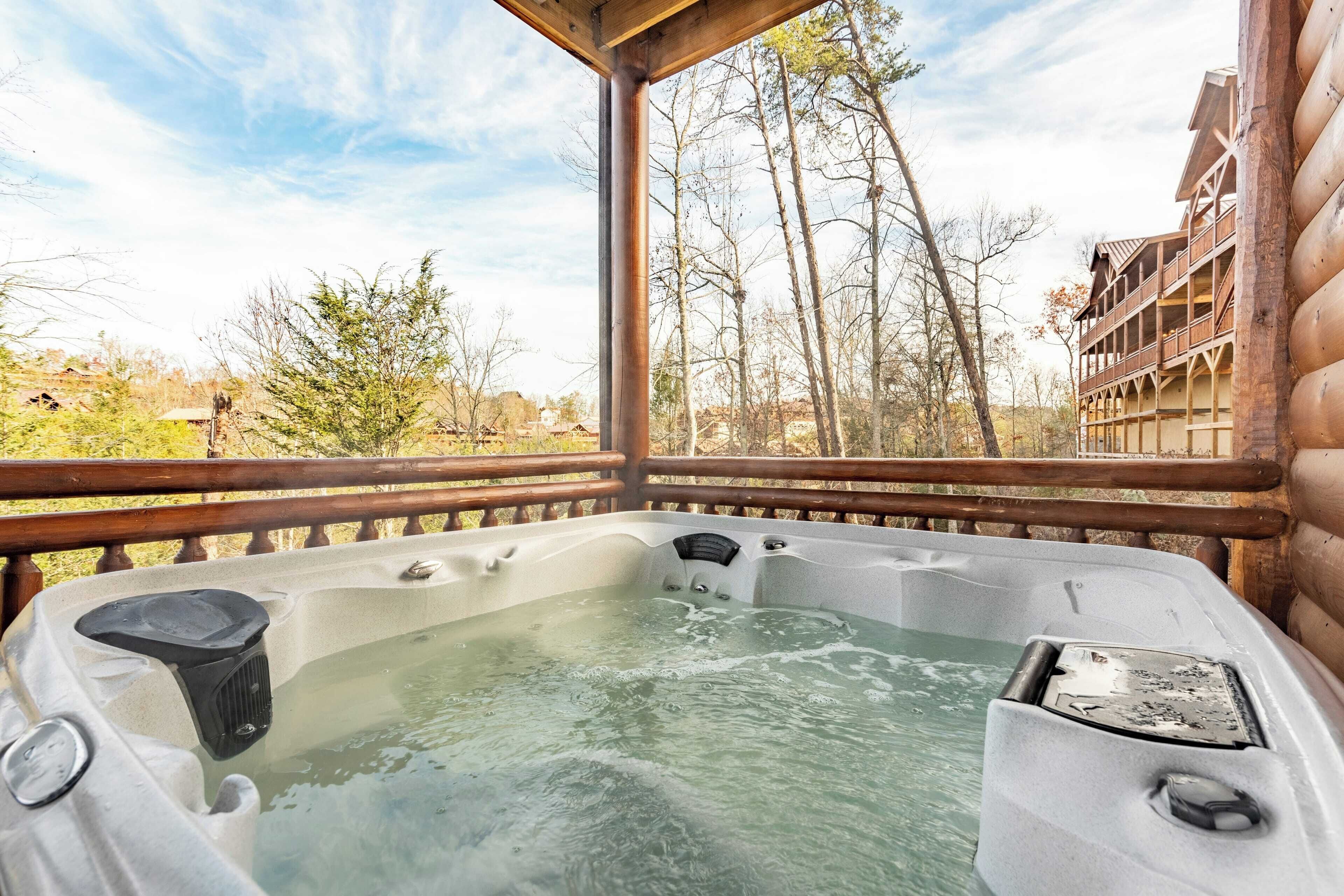 Ein Whirlpool mit einer Holterrasse und Blick auf Bäume und Gebäude.