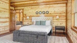 A wooden cabin bedroom with a large bed, two bedside tables, and a wicker ottoman. - Ridge View by Avantstay15mins From Pigeon Forge w/ Pavilion, Indoor Pool & Hot Tub! (Sevierville)