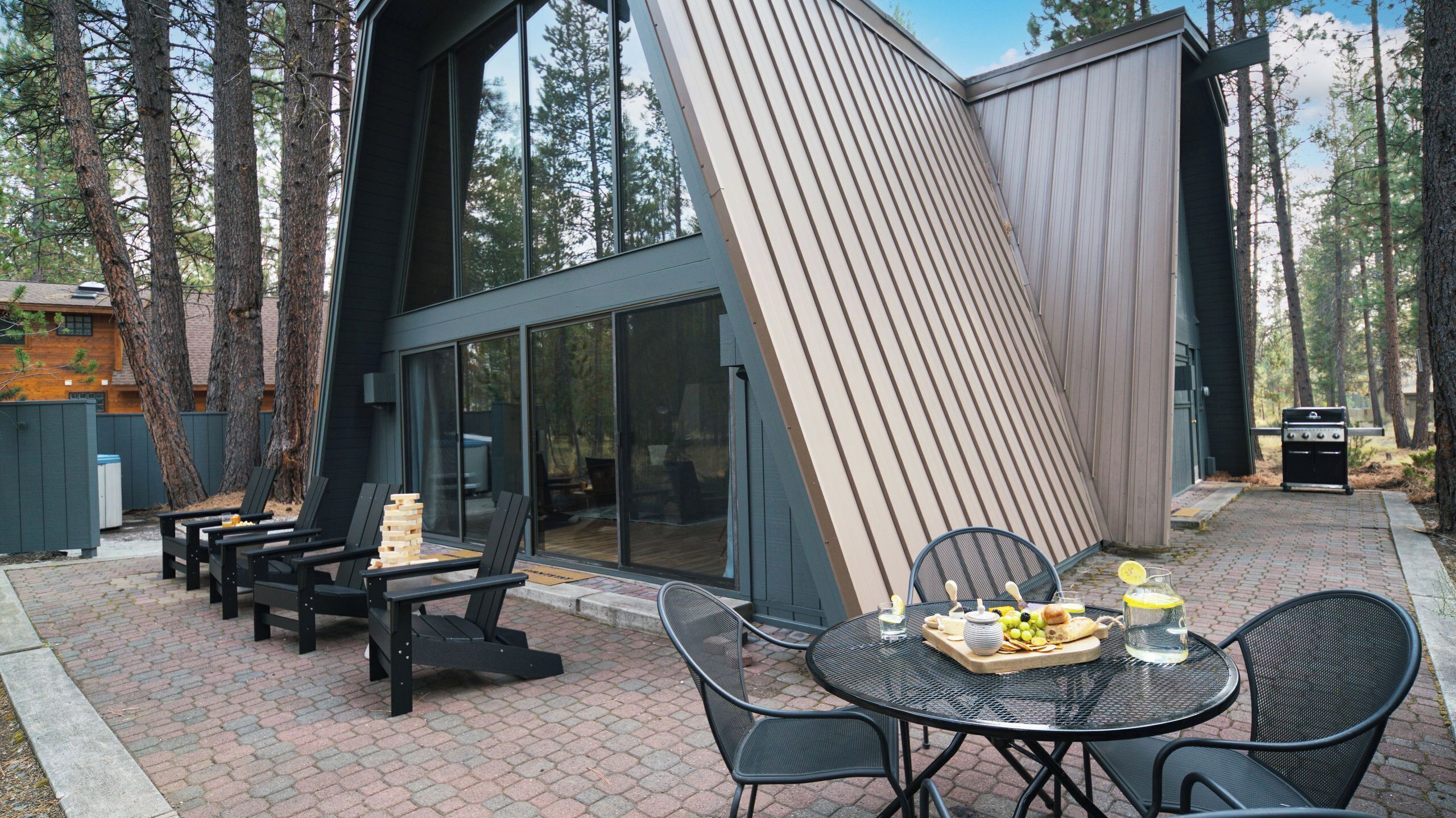 A modern outdoor patio with a dining table, chairs, and a grill.