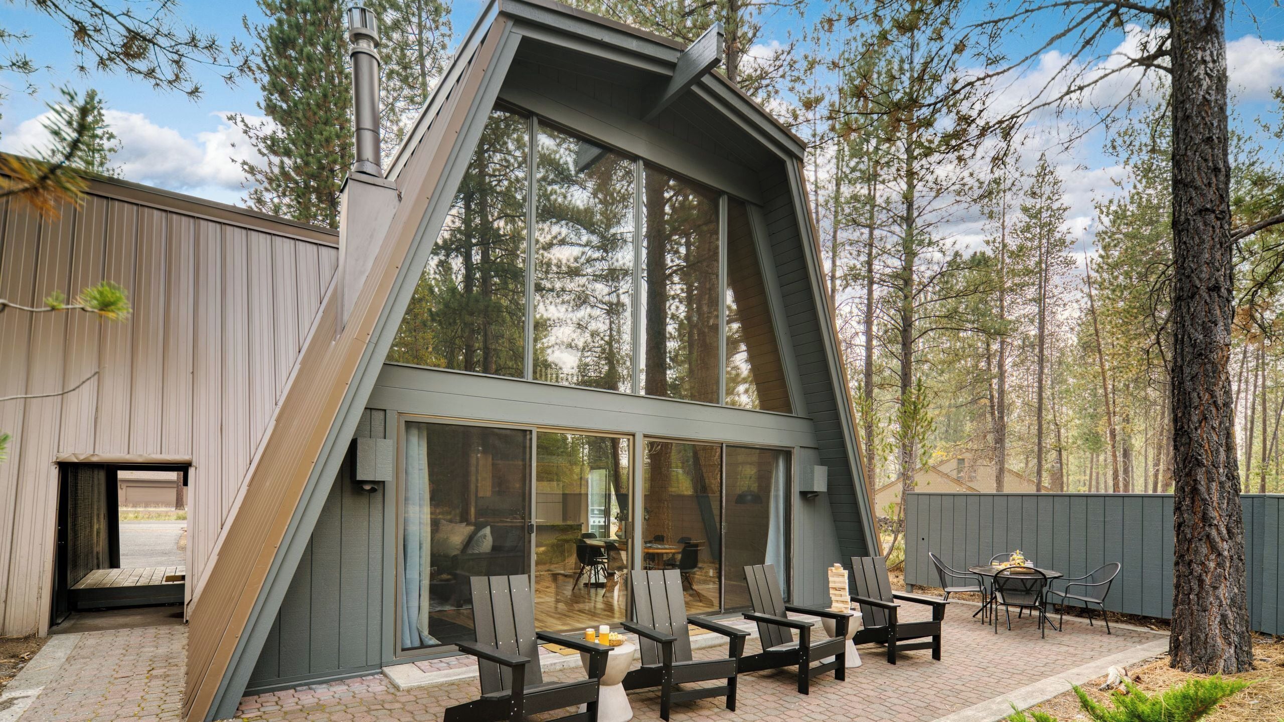 A modern house with a sloped roof, large windows, and a patio with outdoor seating.