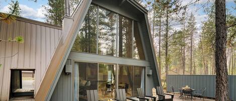 A modern house with a sloped roof, large windows, and a patio with outdoor seating.