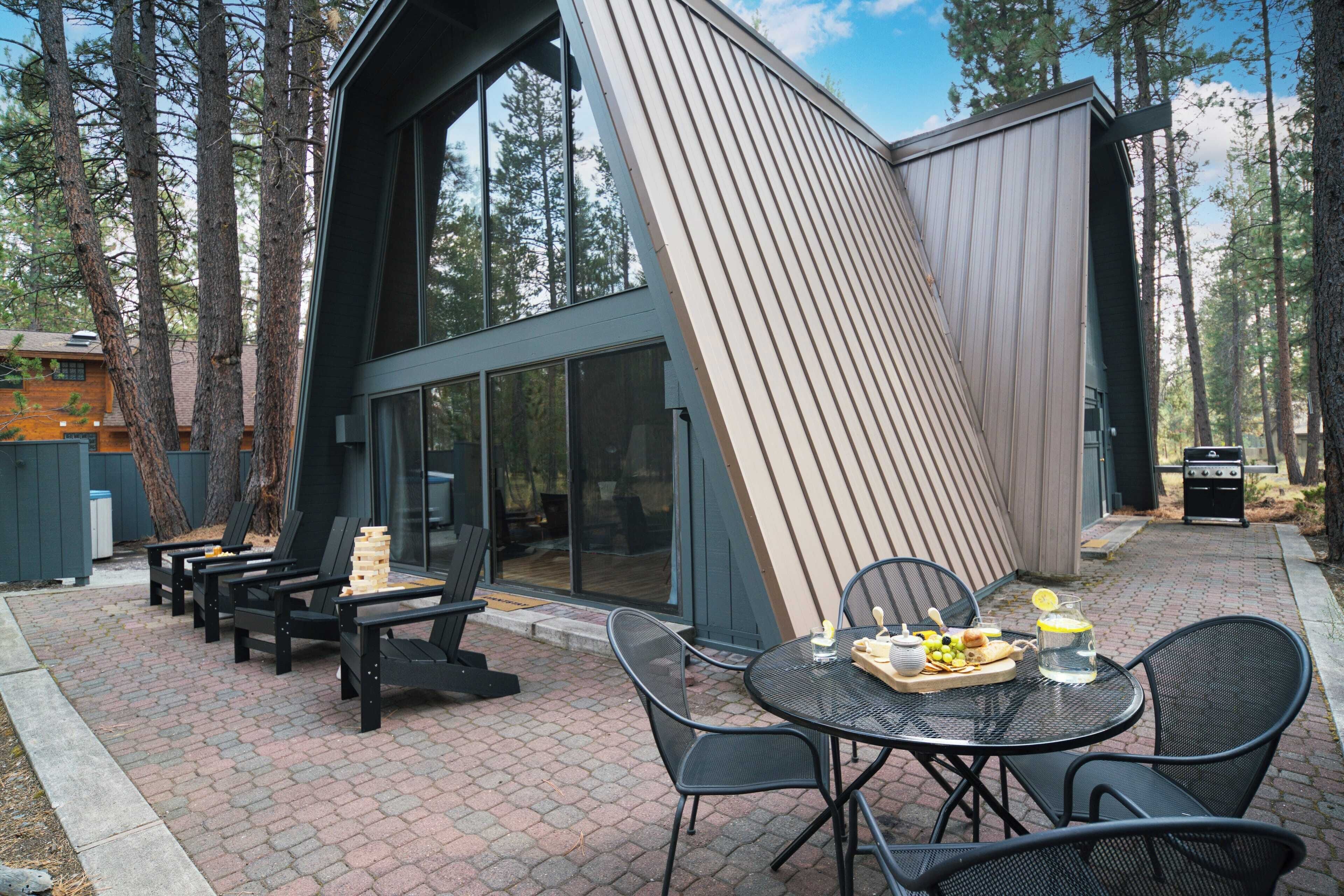A modern outdoor patio with a dining table, chairs, and a grill area.
