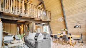 A spacious loft with a wooden interior, a balcony, a dining area, and a cozy seating arrangement. - Alder by Avantstay Hot Tub + Fireplace + Foosball Loft + Patio Grill Walk to Sunriver Village + Trails + Mt. Bachelor 30 Min (Bend)