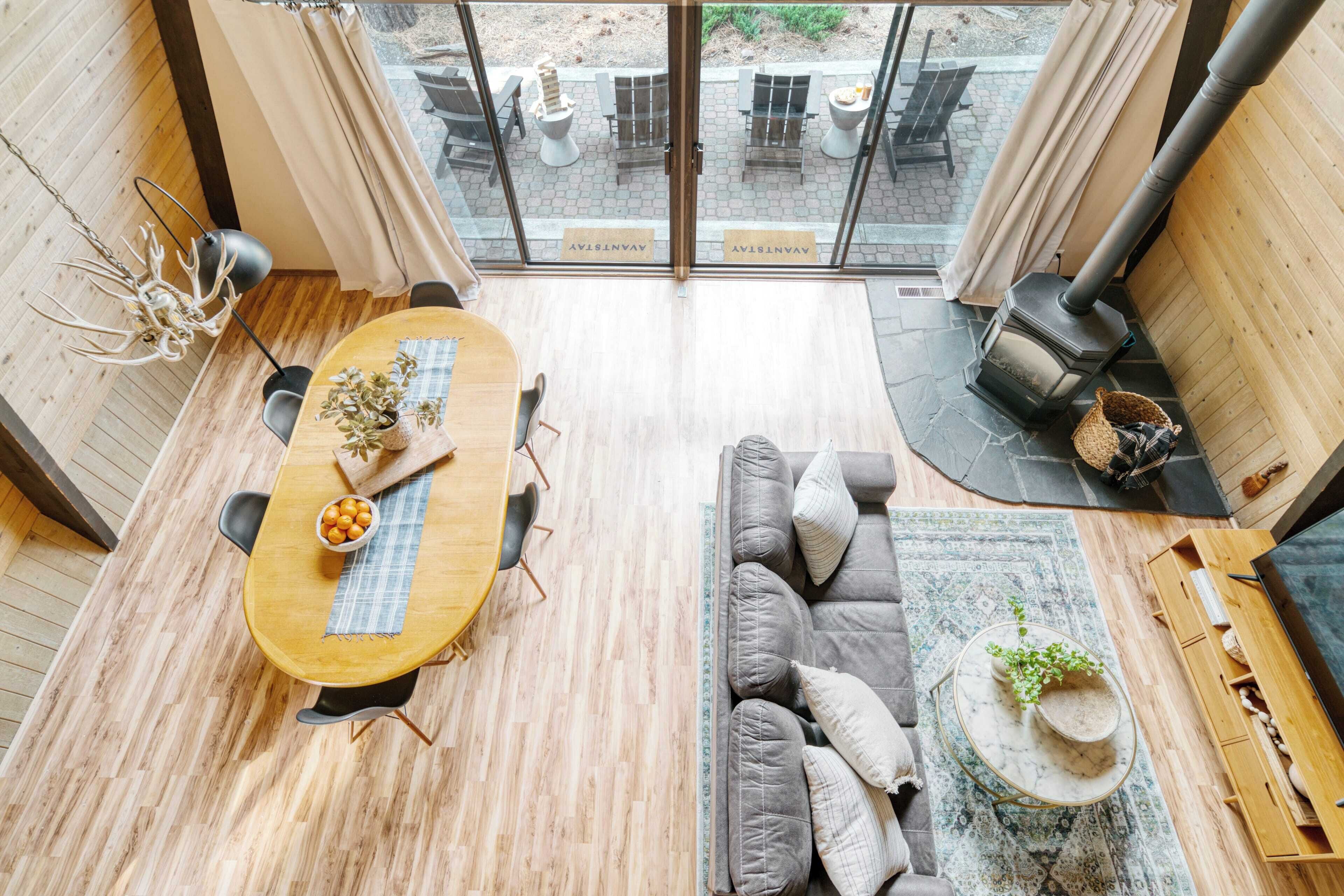 Ein modernes Interieur mit einem Holzesstisch, einem grauen Sofa und einem Kaminofen.