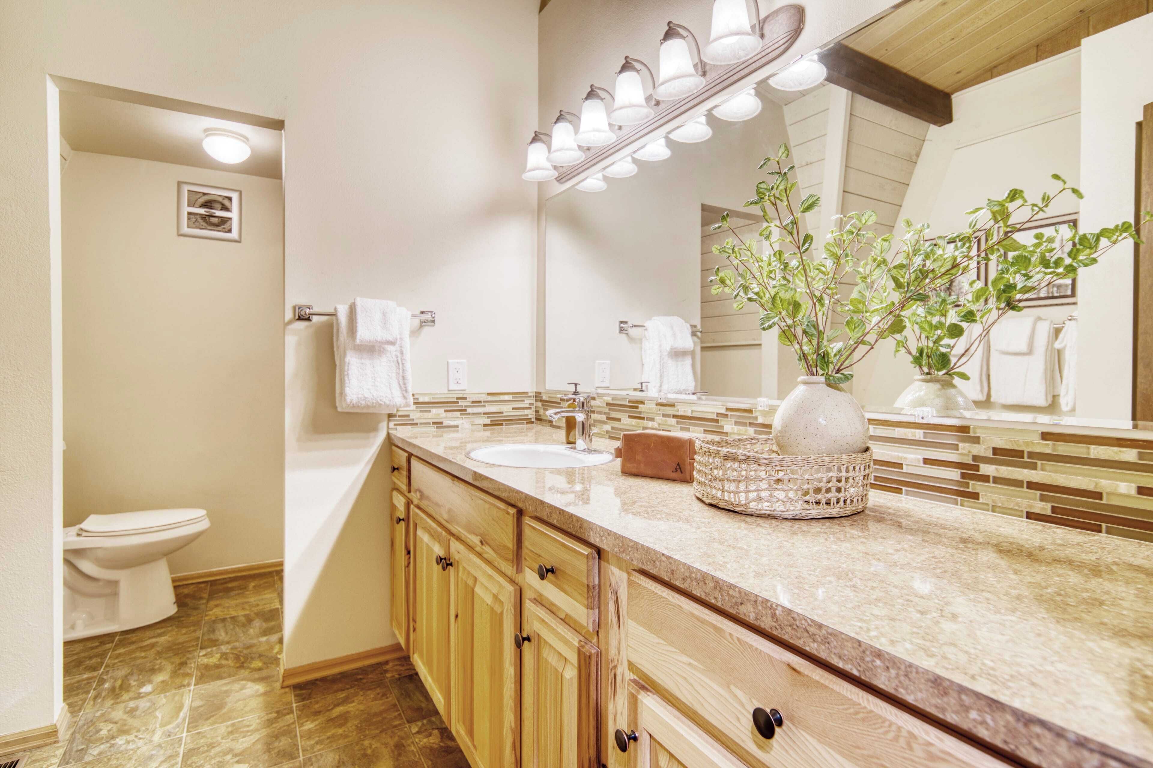 A bathroom with a sink, mirror, towel rack, and a potted plant.