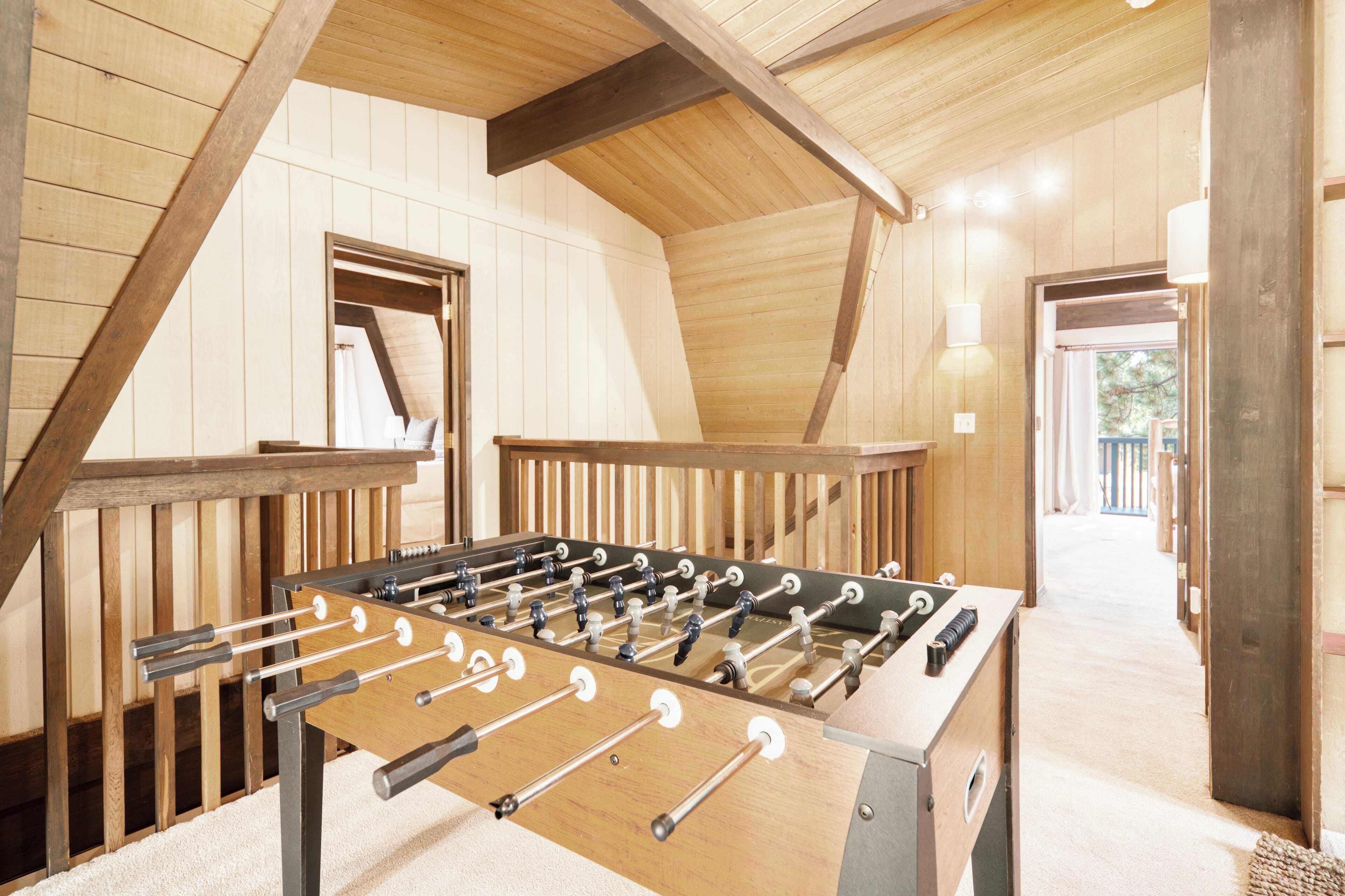 Une table de baby-foot dans une pièce aux murs en bois et au plafond en pente.