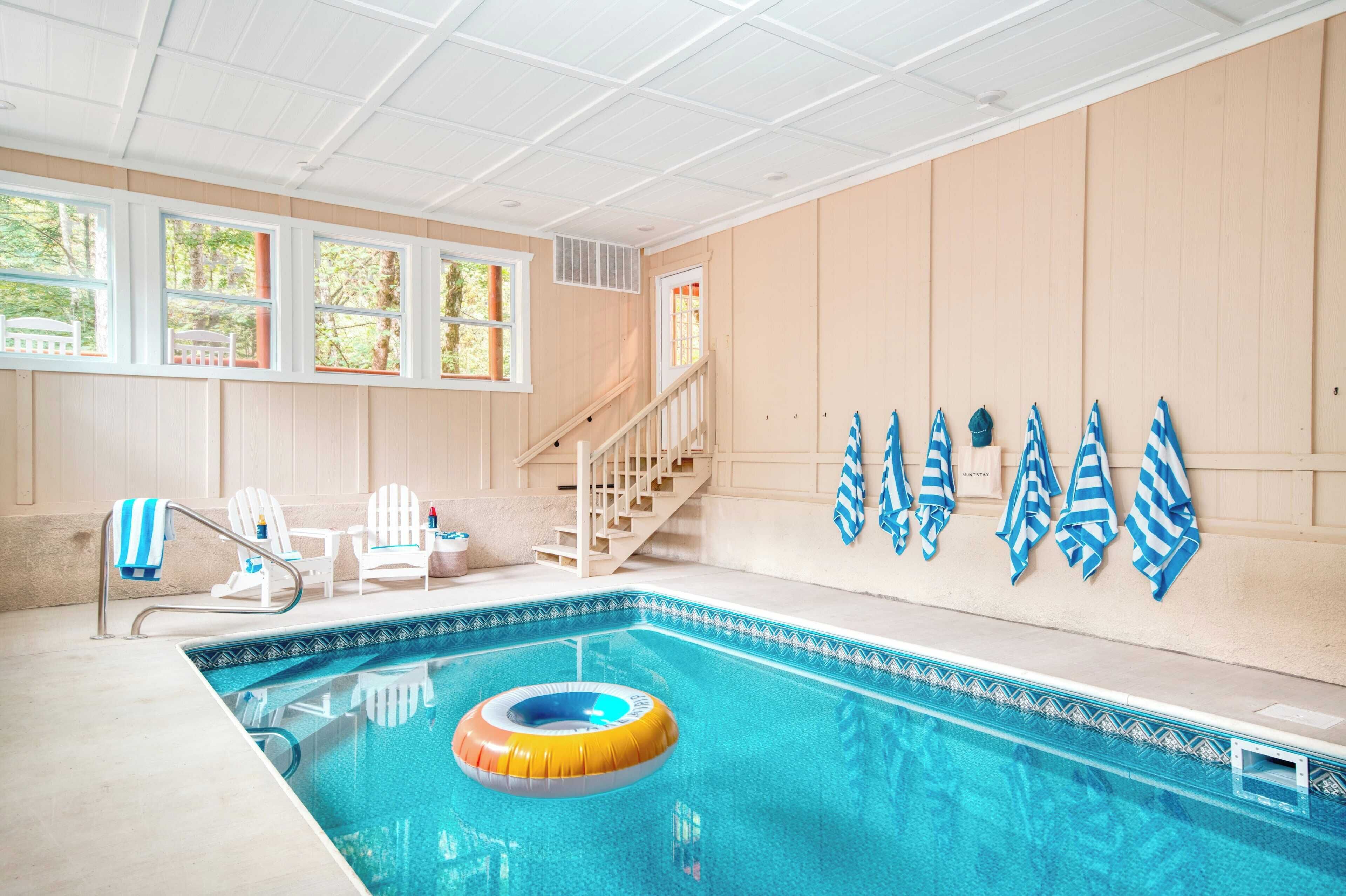 An indoor swimming pool with a wooden interior, a staircase, and a row of towels on the wall.