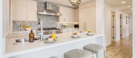 Una cocina moderna con una isla central, electrodomésticos de acero inoxidable y un salpicadero con diseño.