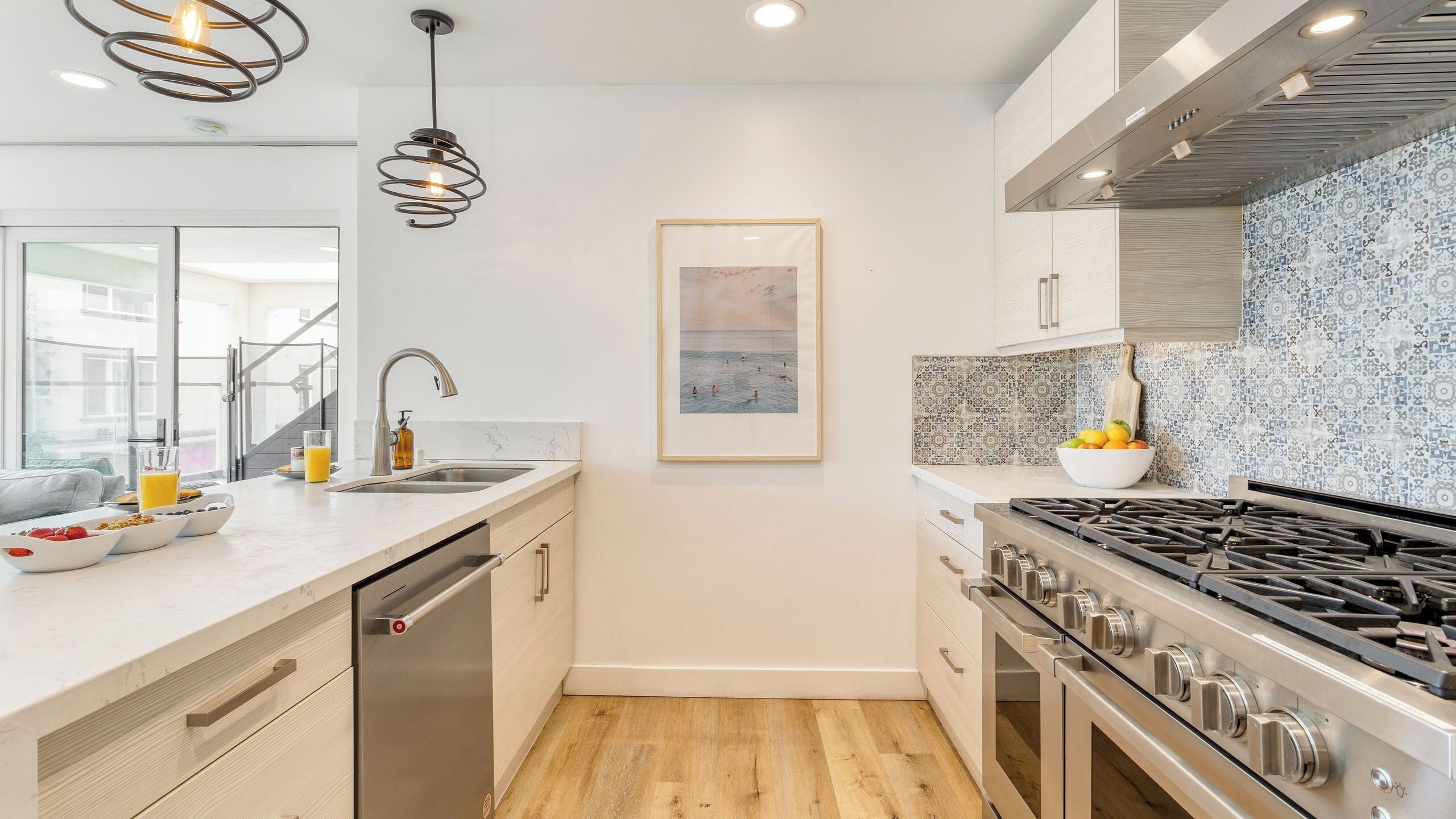 Una cocina moderna con estufa de acero inoxidable, un fregadero y un cuadro en la pared.