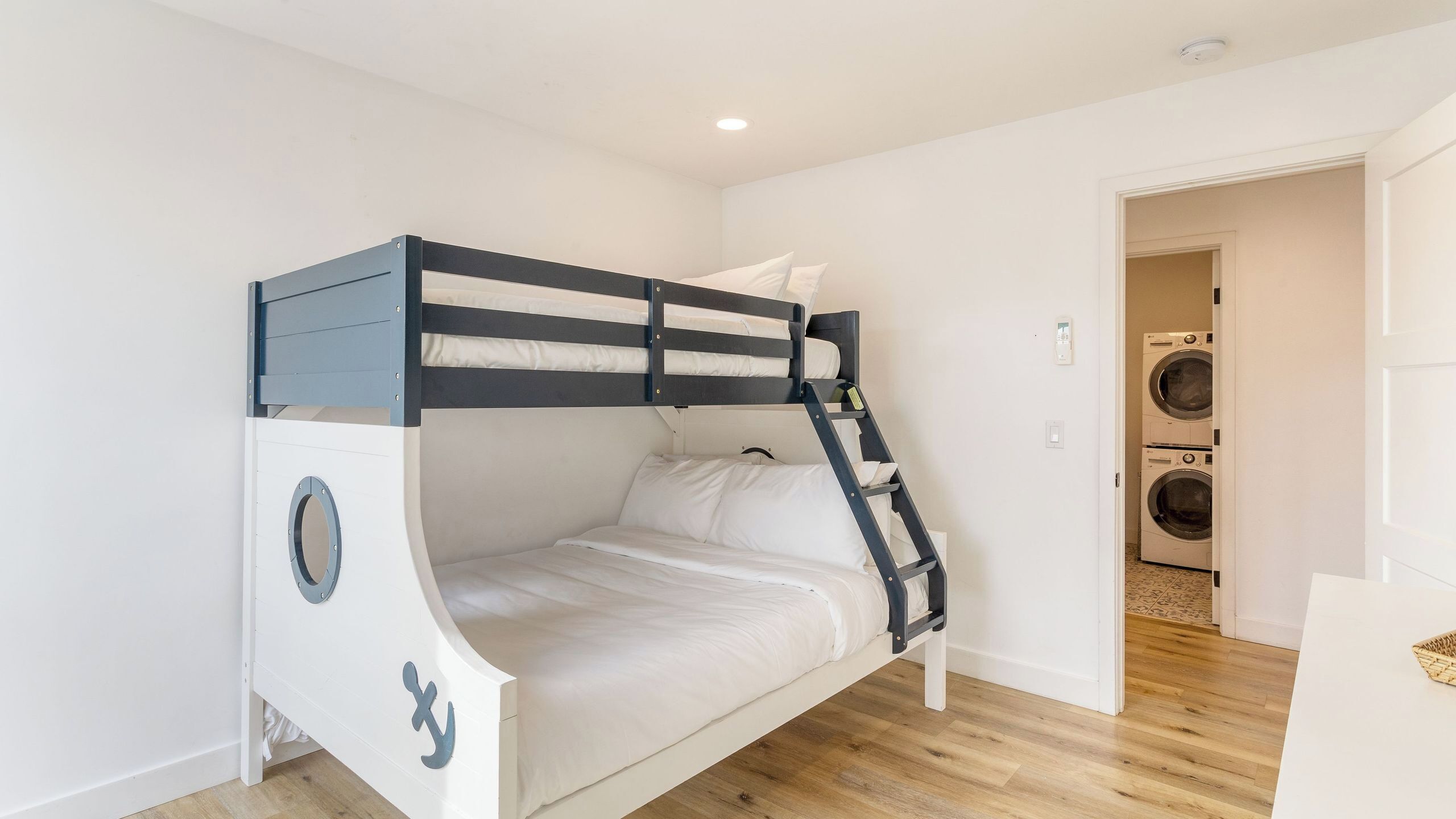 A bunk bed with a ladder, a washing machine, and a door leading to another room.