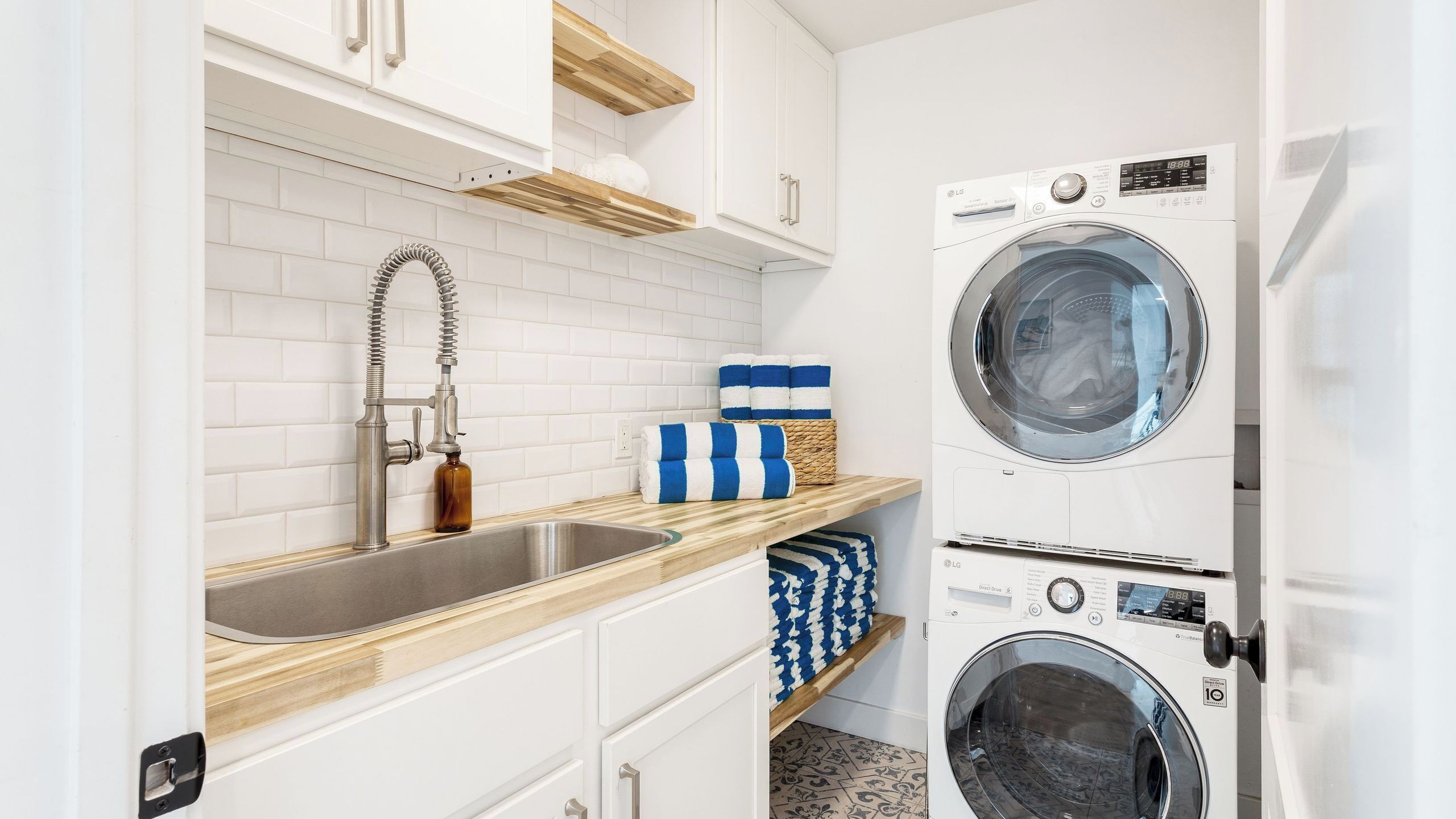 A laundry room with a washing machine, a sink, and storage shelves.