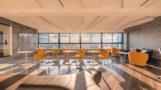 Eine moderne Lounge mit Stadtblick, ausgestattet mit verschiedenen Sitzgelegenheiten und einem großen Fenster.