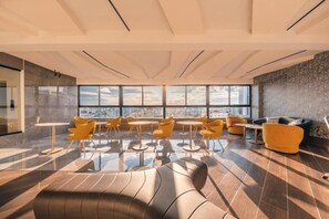 Eine moderne Lounge mit Stadtblick, ausgestattet mit verschiedenen Sitzgelegenheiten und einem großen Fenster.