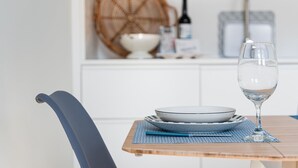 A dining table with a glass of water, plates, and a bottle.