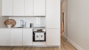 A modern kitchen with white cabinetry, a built-in oven, and a sink.